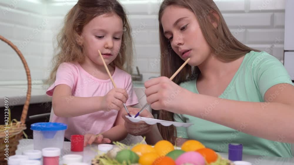Happy easter. Two sisters painting Easter eggs. Happy family children preparing for Easter. Cute little child girl wearing bunny ears on Easter day. Happy easter. Two sisters painting Easter eggs. Happy family children preparing for Easter. Cute little child girl wearing bunny ears on Easter day.