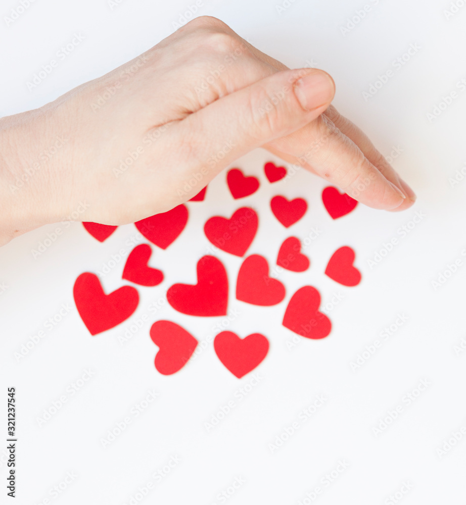 Valentine's Day background. Women's hands hold many red hearts in the palm against the white background. Concept of saving love