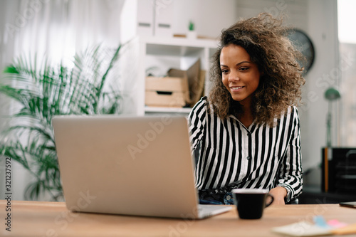 Young businesswoman in office. African beautiful woman using lap top. 