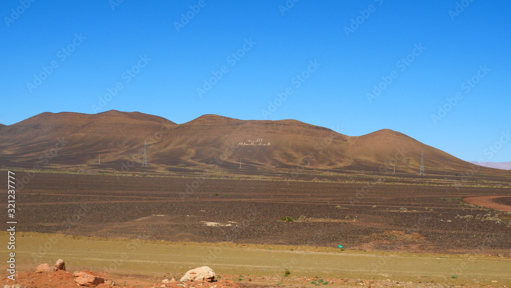 Obraz premium Bright landscape of Morocco, breathtaking curves of mountains, stunning combination of hills & farm land,inadvertent distribution of houses & huts, raw impression of pure nature.