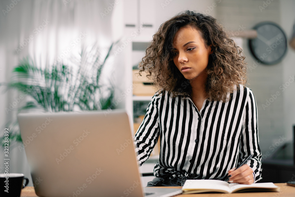 African businesswoman in office. Beautiful woman working on laptop and taking notes. African businesswoman in office. Beautiful woman working on laptop and taking notes.