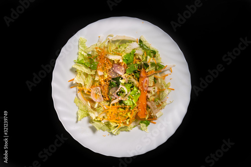  Mixed salad, fresh, light and colorful, in a white plate, on a black background