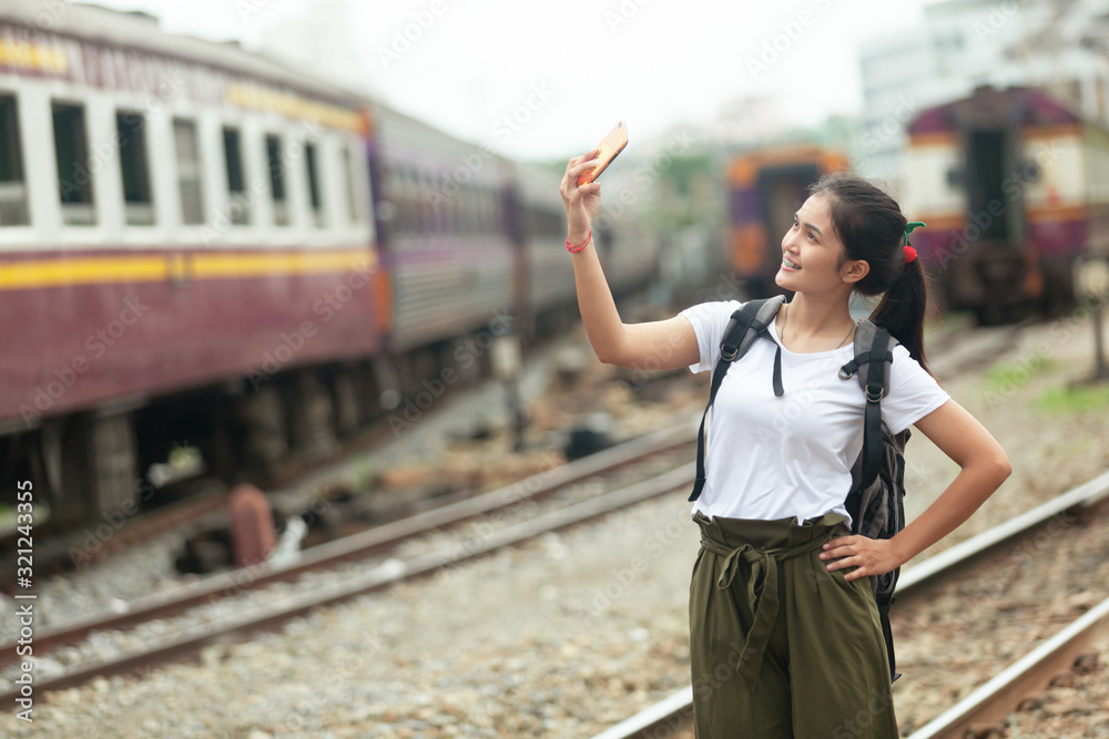 asian girl are taking pictures at the train station before traveling by train, destination nature trip in summer