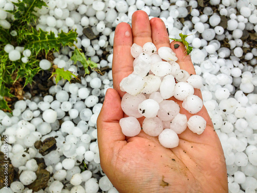 Big hailstones in the hand with hailstones in background