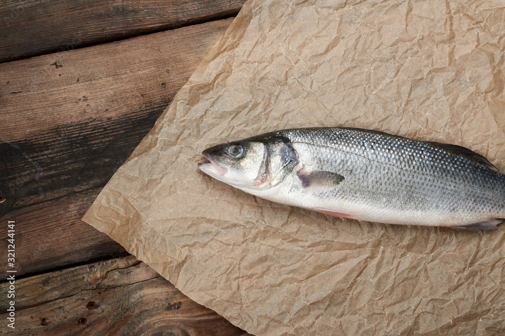 fresh whole sea bass fish on brown crumpled paper fresh whole sea bass fish on brown crumpled paper