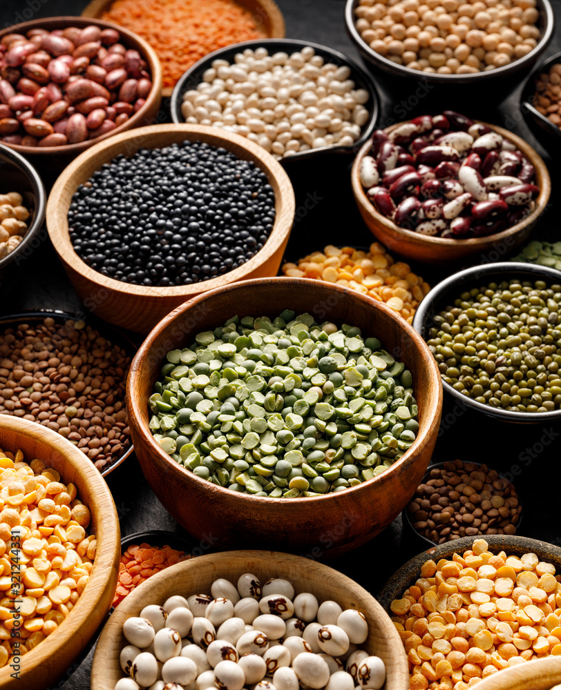 Legumes, a set consisting of different types of beans, lentils and peas on a black background, close up. The concept of healthy and nutritious food