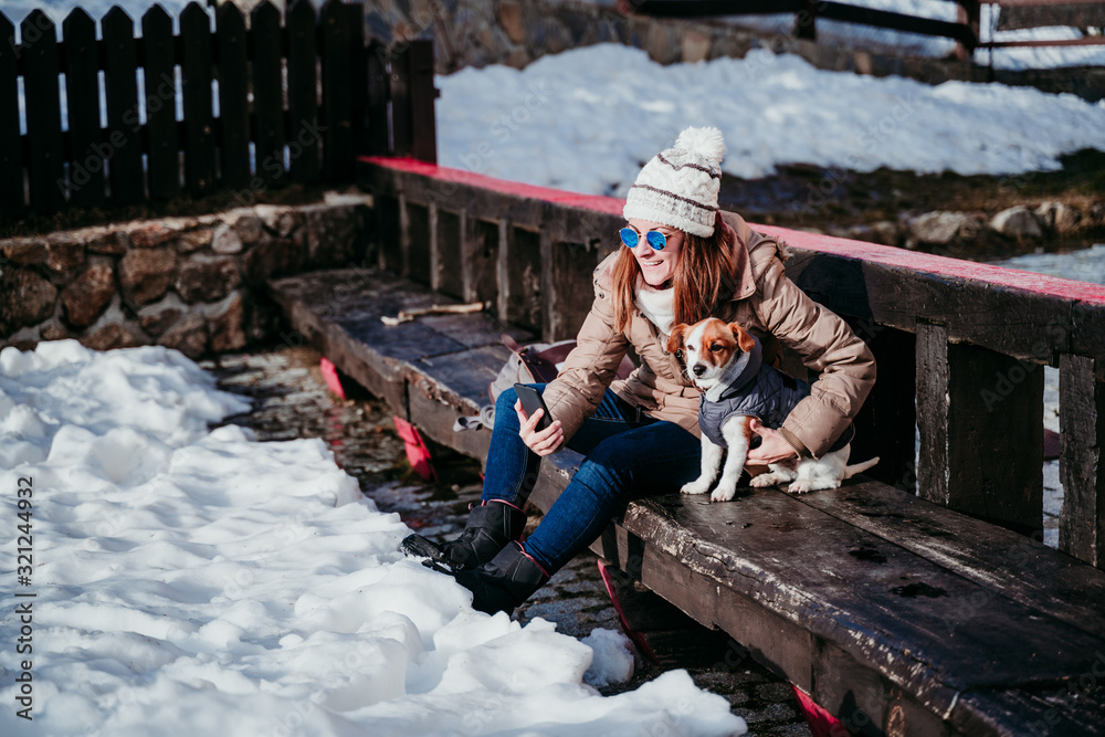 woman and cute jack russell dog enjoying outdoors at the mountain with snow. winter season. woman taking self portrait with mobile phone woman and cute jack russell dog enjoying outdoors at the mountain with snow. winter season. woman taking self portrait with mobile phone