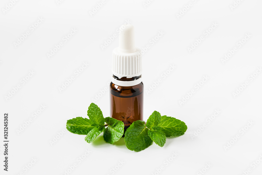 isolated glass bottle with aromatic oil and a sprig of mint on a white background isolated glass bottle with aromatic oil and a sprig of mint on a white background