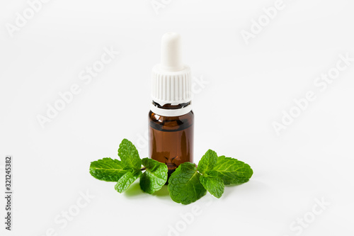 isolated glass bottle with aromatic oil and a sprig of mint on a white background