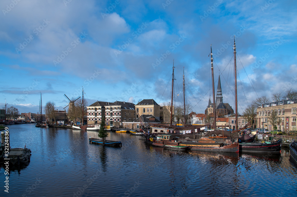 Museum harbor and Turfsingelgracht in Gouda with historic boats, De Roode Leeuw flour mill and the Gouwekerk.
