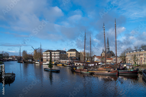 Museum harbor and Turfsingelgracht in Gouda with historic boats  De Roode Leeuw flour mill and the Gouwekerk.