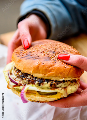 Woman hand holding a fresh burger before eating on street cafe
