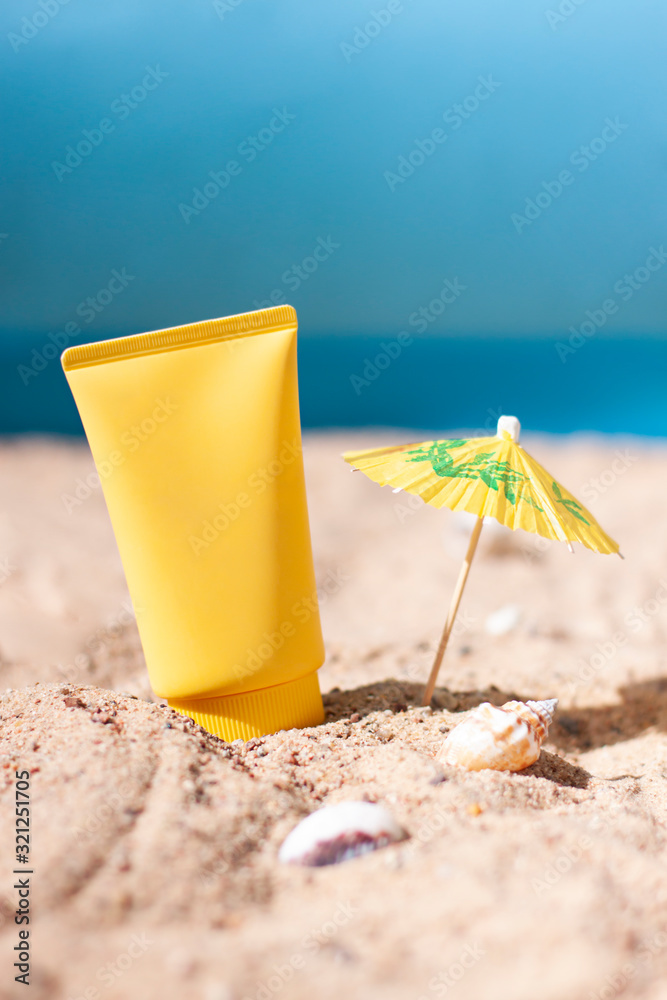 Yellow tube of sun cream in the beach in sand close up. Sunscreen cosmetics concept Yellow tube of sun cream in the beach in sand close up. Sunscreen cosmetics concept