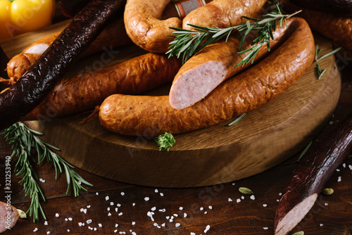 Different smoked sausages with vgetables and ingredients on wooden background