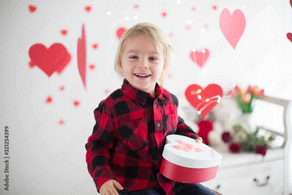 Cute blonde toddler boy, holding box in heart shape and flowers Cute blonde toddler boy, holding box in heart shape and flowers