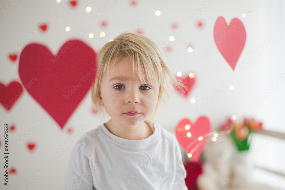 Cute blonde toddler boy, holding box in heart shape and flowers Cute blonde toddler boy, holding box in heart shape and flowers