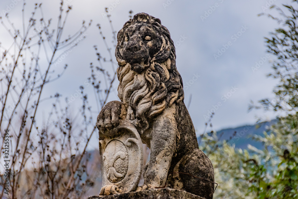 Puget-Theniers, France - January 23, 2020: A statue of a lion holding the 'fleur-de-lis' emblem ('fleur-de-lys'; Iris versicolor)