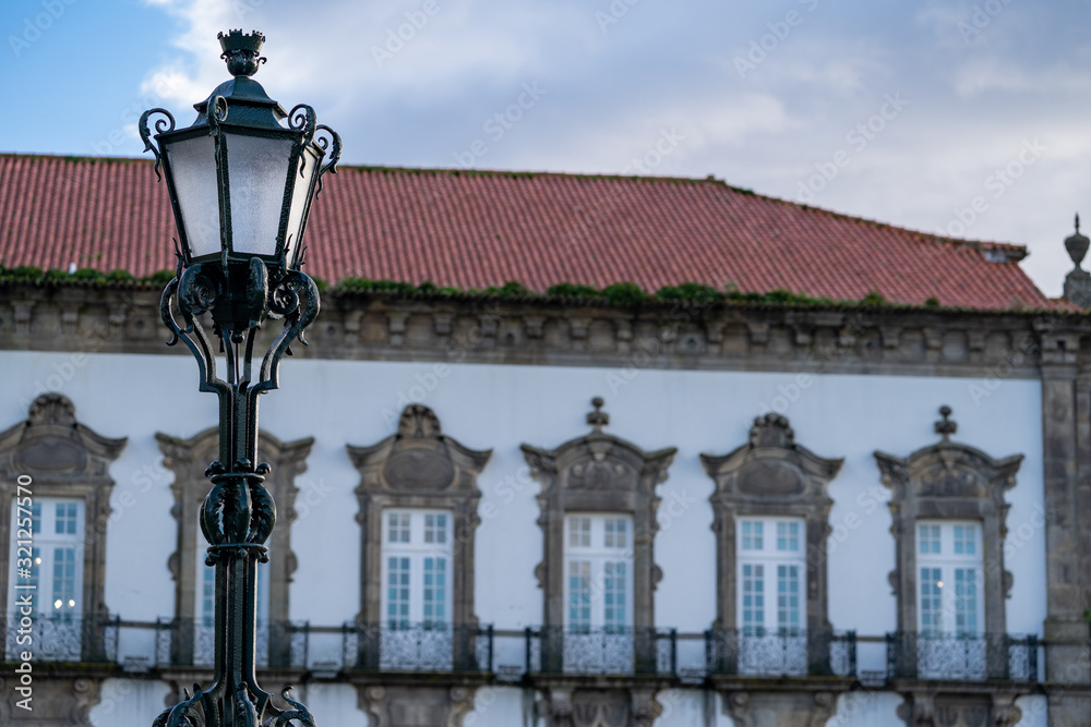 Selective focus on an ornate street lamp with traditonal Portugal building blurred in background at sunset in Porto, Portugal