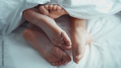 couple in bed making love. male and female legs top view, white linens. sexy . Cute shoot photo