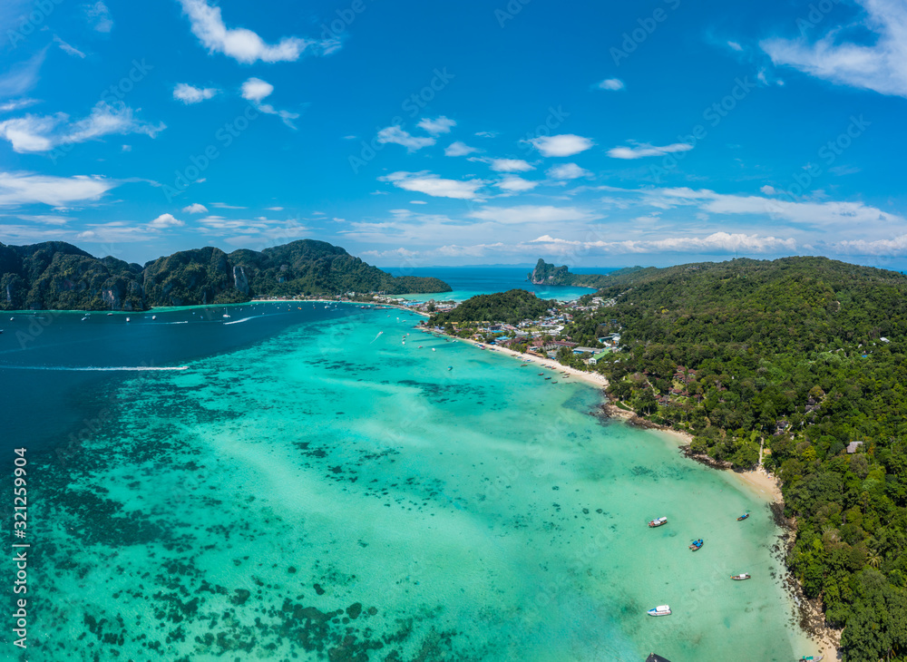 Top view of tropical island with limestone rocks and blue clear water. Aerial view of Tonsai bay with many boats and speedboats above coral reef. Phi-Phi Don Island, Thailand.