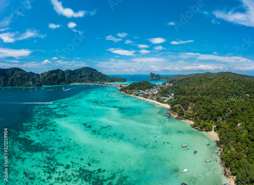 Top view of tropical island with limestone rocks and blue clear water. Aerial view of Tonsai bay with many boats and speedboats above coral reef. Phi-Phi Don Island, Thailand.