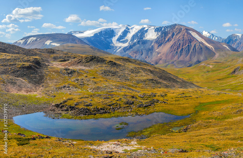 Mountain view. A lake among the mountain tundra and alpine steppe. Snow-capped peaks and picturesque sky. © Valerii