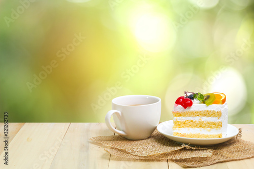 Slice cake with coffee cup on wood , green blur background