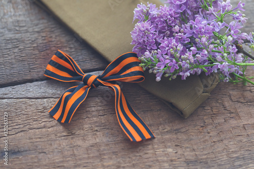 Traditional Saint George ribbon on old wooden background with lilac branch, Victory Day, May 9, selective focus photo