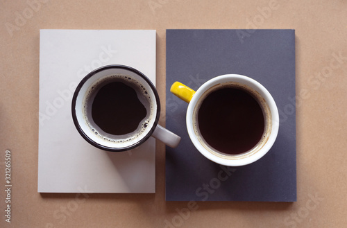 Two cups of coffee on books. Top view of the workspace.