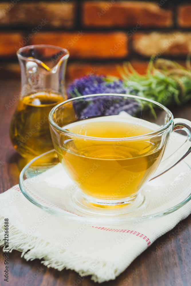 A cup of lavender tea and jar of honey with a bunch of lavender in the background