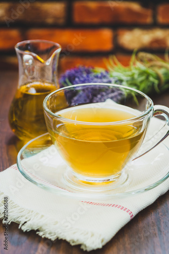 A cup of lavender tea and jar of honey with a bunch of lavender in the background