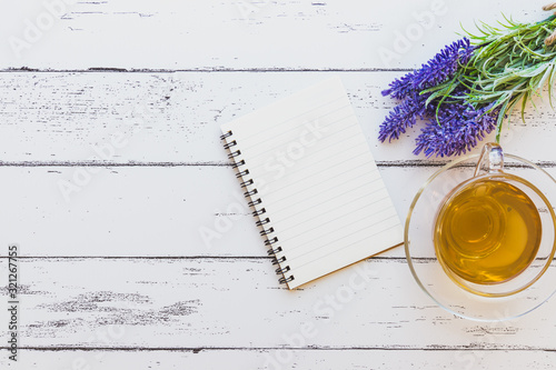 A cup of lavender tea with a notebook and a bunch of  lavender on white wooden background (Flat lay and copy space)