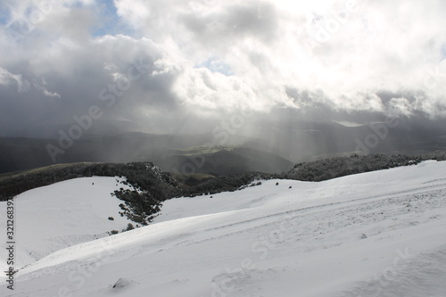 Snowy hillside with sun rising and clouds