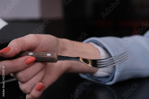 Woman hand with fork on street cafe background