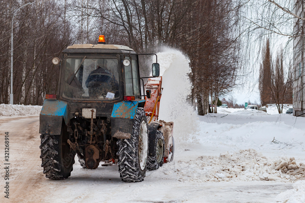Snow cleaning tractor removing snow with front shovel on a city street after blizzard. Russia, Republic Of Bashkortostan. Snow removal in the city Snow cleaning tractor removing snow with front shovel on a city street after blizzard. Russia, Republic Of Bashkortostan. Snow removal in the city