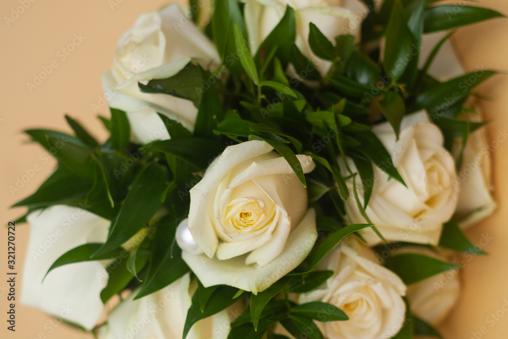 wedding bouquet of white roses decorated with pearls lies on a background of delicate pastel peach color. wedding decoration with natural flowers work of a florist decorator wedding bouquet of white roses decorated with pearls lies on a background of delicate pastel peach color. wedding decoration with natural flowers work of a florist decorator