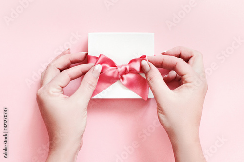 Hands tying a bow on a white gift box