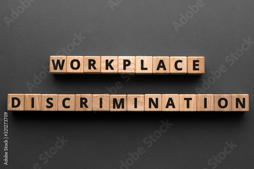 Workplace discrimination - words from wooden blocks with letters, employment discrimination legislation and issues concept, top view gray background