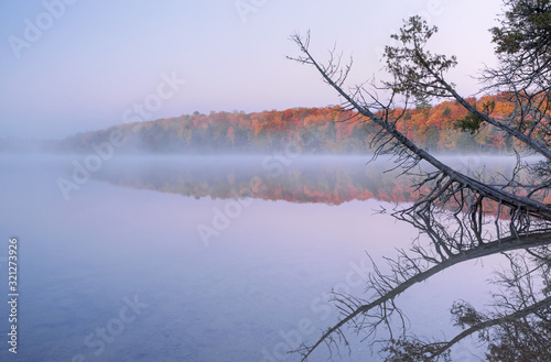 Autumn landscape at dawn of Pete's Lake in fog with mirrored reflections in calm water, Hiawatha National Forest, Michigan's Upper Peninsula, USA