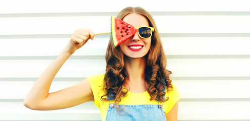 Portrait happy smiling young woman covering her eye with ice cream shaped watermelon over white background