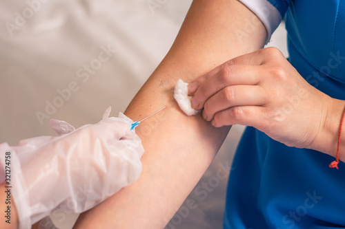 A nurse injects a colleague into a vein. The concept of vaccination against dangerous diseases. Injection into a vein is a close-up.