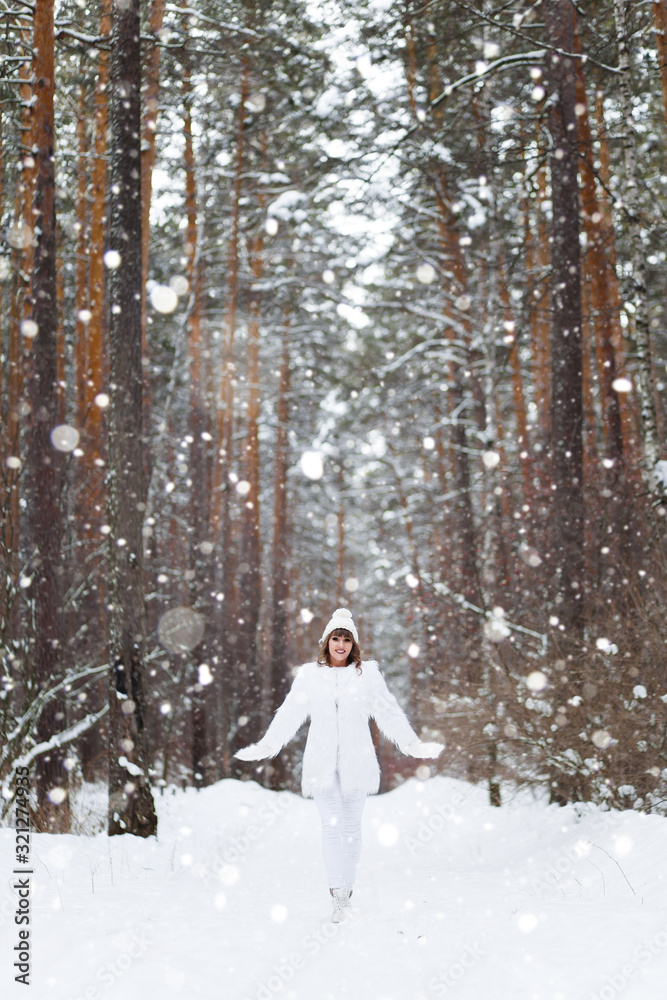 A beautiful pretty young girl with curly hair and a snow-white smile in a white warm coat is walking and fooling around in the winter forest against the background of snow and trees, enjoy A beautiful pretty young girl with curly hair and a snow-white smile in a white warm coat is walking and fooling around in the winter forest against the background of snow and trees, enjoy