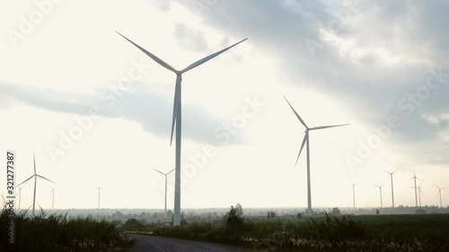 Wind turbine farm and agricultural fields on blue sky.