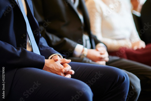 Gefaltete Hände eines Mannes während einer Hochzeit
