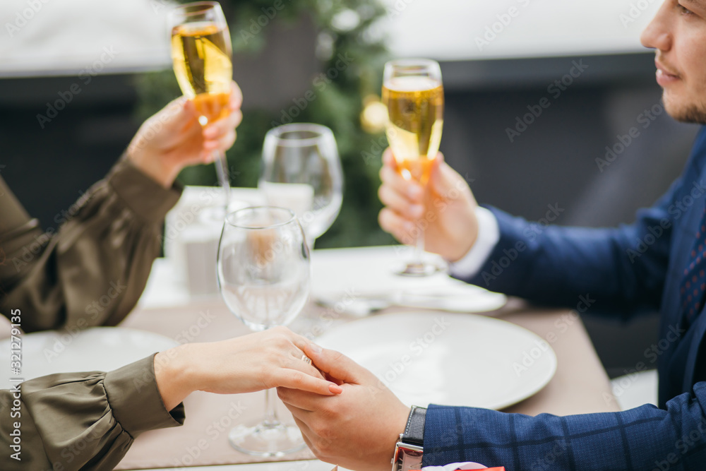 close-up of couple clinking glasses with champagne in rich representative restaurant. couple having dinner together, on a date close-up of couple clinking glasses with champagne in rich representative restaurant. couple having dinner together, on a date