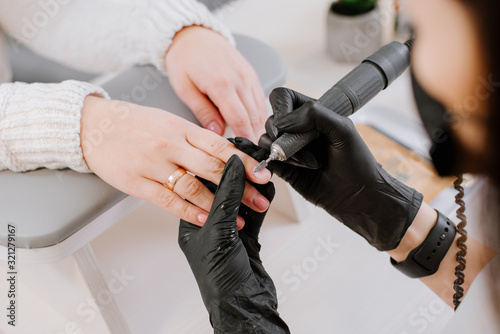 Woman use electric nail file drill in beauty salon. Nails manicure process in detail