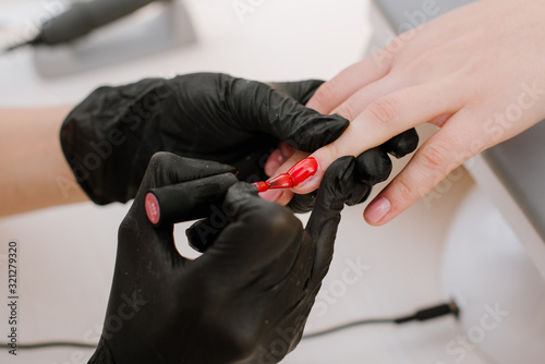 Beautician master applying color nail polish. Closeup