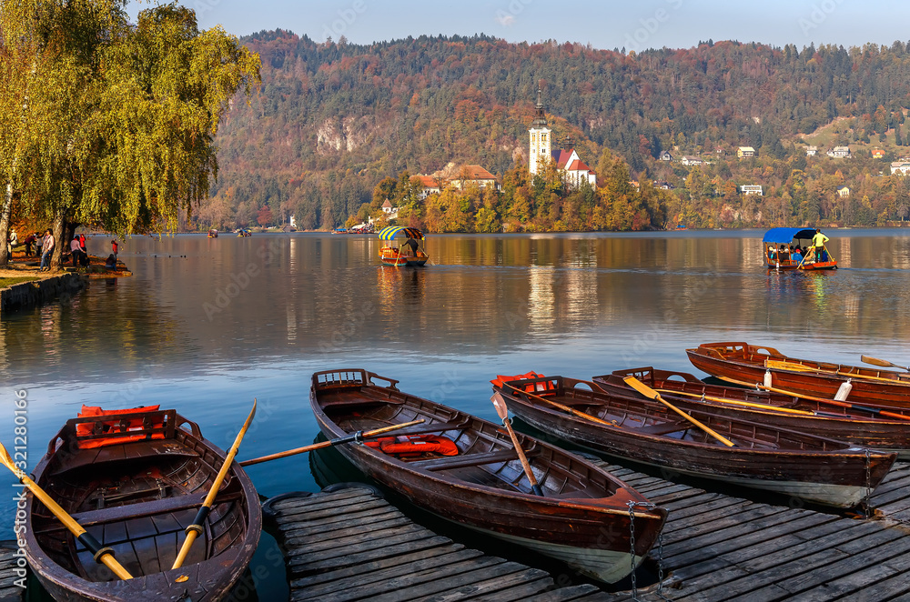 Sunny morning scene on mountains lake. Boats at the pier of the Bled Island, Lake Bled, Slovenia. popular touristic place. summer view of  Blejsko jezero. is a glacial lake in the Julian Alps