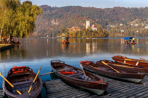 Sunny morning scene on mountains lake. Boats at the pier of the Bled Island, Lake Bled, Slovenia. popular touristic place. summer view of  Blejsko jezero. is a glacial lake in the Julian Alps