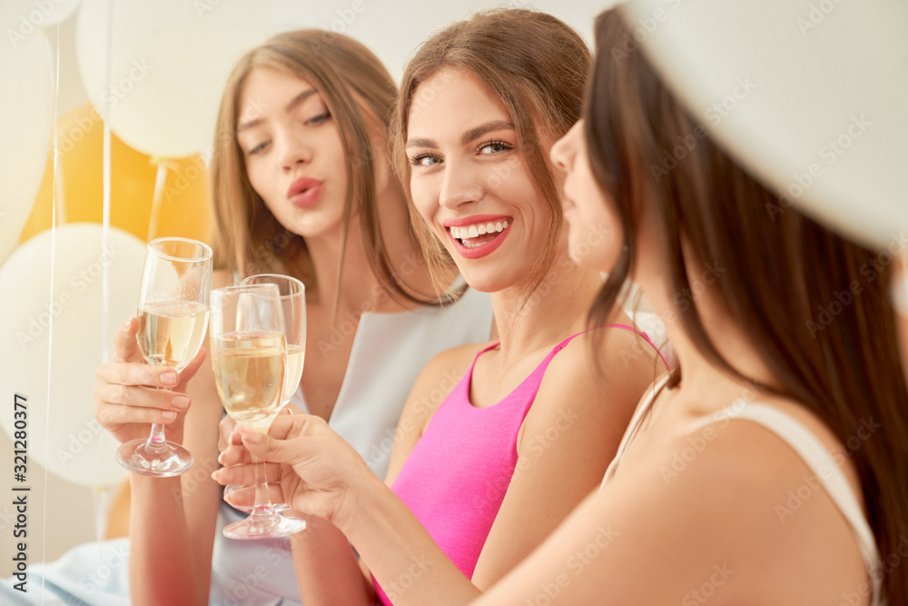 Crop of girlfriends drinking wine in room. Crop of girlfriends drinking wine in room.